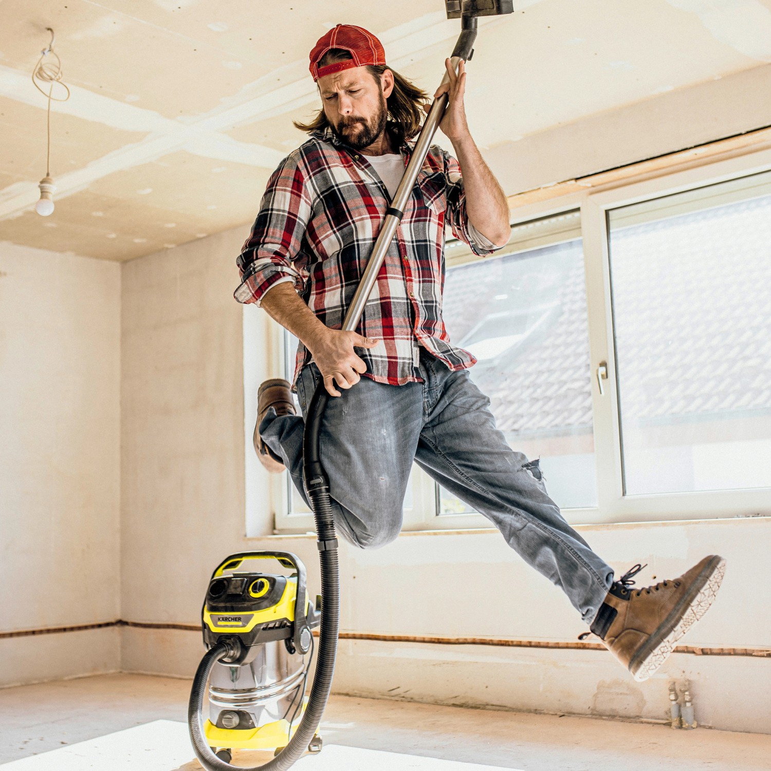 Mann springt mit Kärcher WD 6 P S V-30/6/22/T Nass-Trockensauger in der Luft.