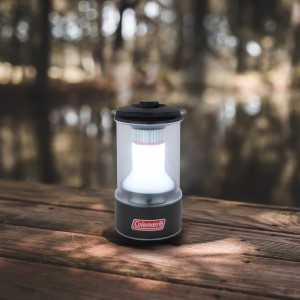 Leuchtende Coleman Camping Laterne 600L auf Holzuntergrund, ideal für Camping & Outdoor.