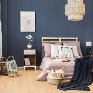 Verlegter ECO4ALL Pro Vinylboden Eiche Milano im Schlafzimmer mit Bett und Dekoration.