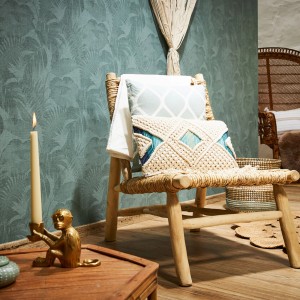 Wohnzimmer mit dunkelgrüner Palmentapete, Holzstuhl und Deko-Elementen.