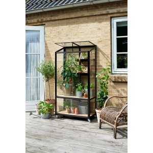 Juliana Urban City Gewächshaus Anthrazit mit Pflanzen auf Terrasse vor Backsteinmauer.