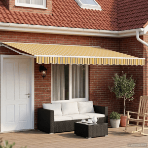 Elektrische Markise in Gelb, Grau, Weiß gestreift, über Terrasse mit Sitzgruppe am Ziegelhaus. Sonnenschutz.