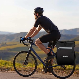Schwarze Wiltec 20L Gepäckträgertasche am Fahrrad eines Radfahrers. Wasserresistente Fahrradtasche, auch als Rucksack nutzbar.