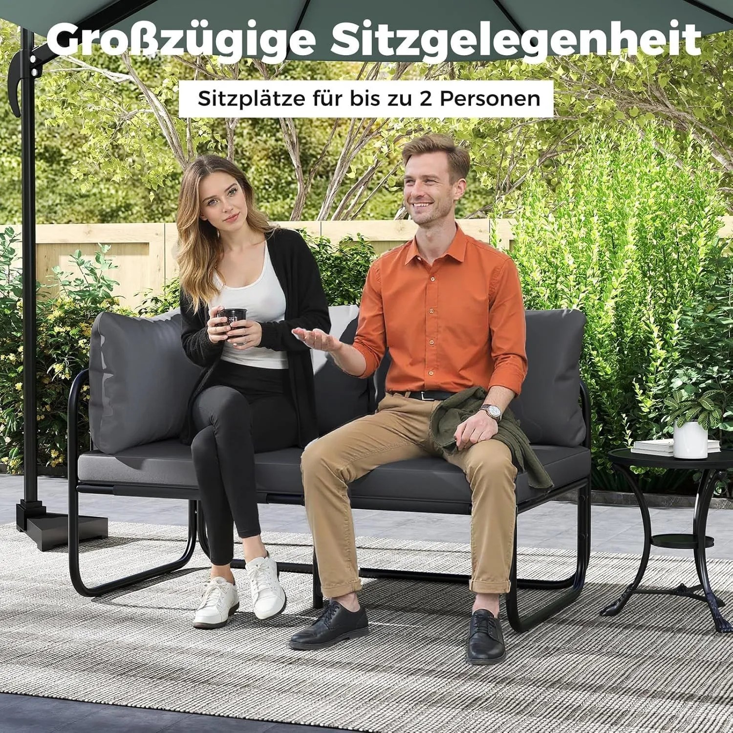 Graues 2-Sitzer Garten Lounge Sofa mit schwarzen Metallrahmen und bequemen Kissen, besetzt von zwei Personen im Garten.