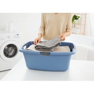 Horizontblaue Rotho Wäschewanne Flowers (50 l) mit Wäsche vor Waschmaschine.
