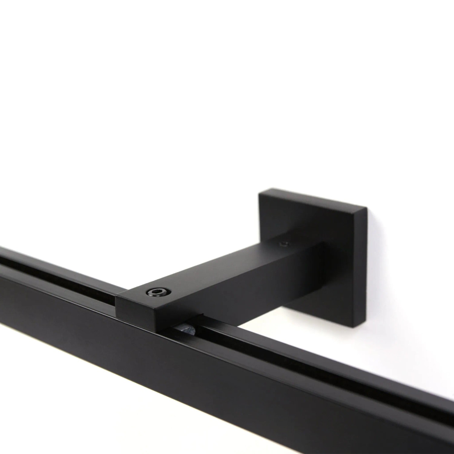 Detailaufnahme: Schwarze Deco-Raum Gardinenschiene Cube mit Halterung an weißer Wand.