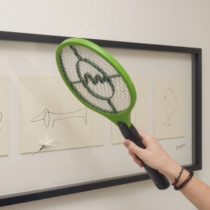 Grüne Gardigo Fliegenklatsche Bzzz in Benutzung gegen eine Mücke vor einem Bild.