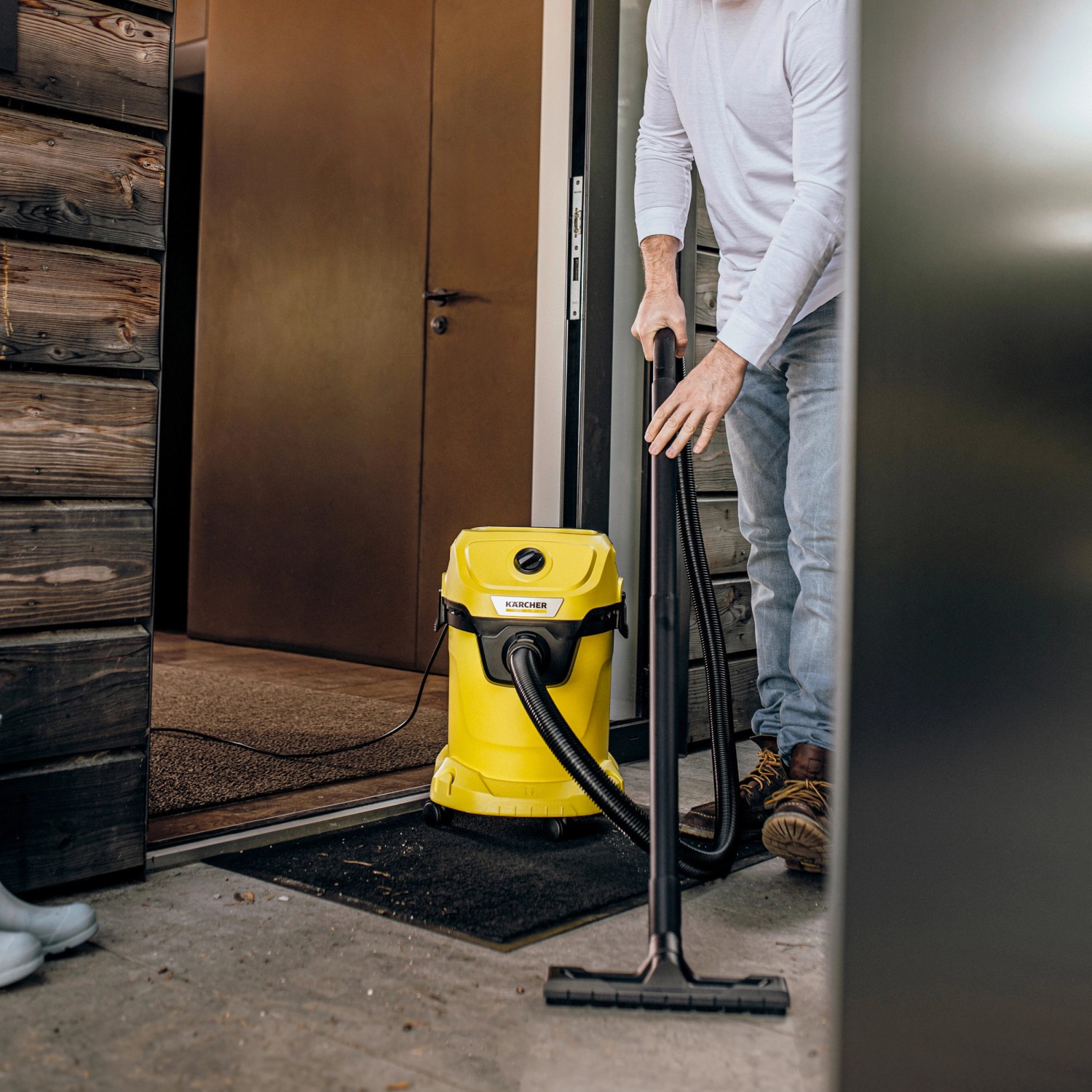 Gelber Kärcher Nass-/Trockensauger WD 3 V-17/4/20 im Einsatz vor einer Haustür.
