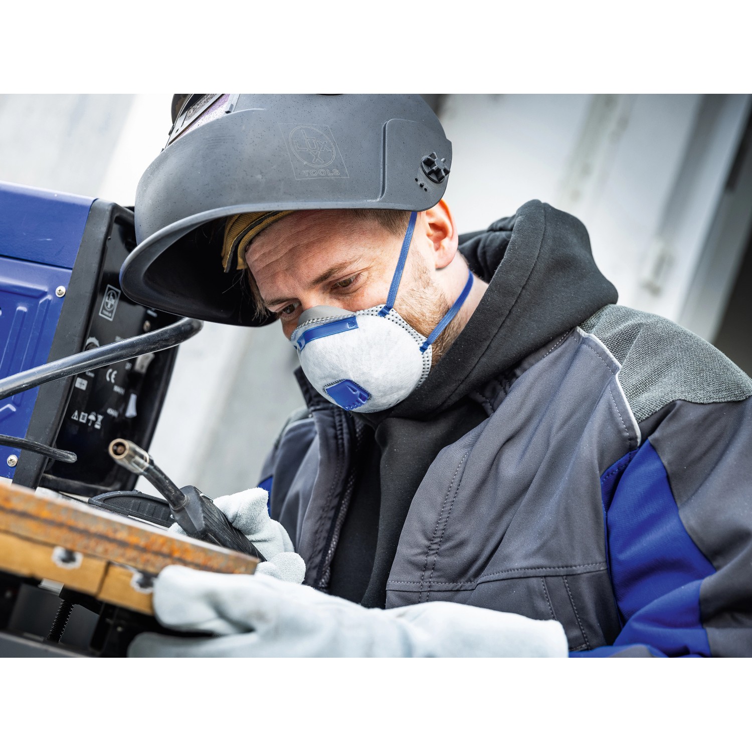 Mann mit Schweißhelm und LUX-TOOLS FFP2 Atemschutzmaske Carbon beim Schweißen.