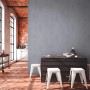 Graue Used Look Vliestapete von PROFHOME im Interieur mit Backsteinwand und weißen Barhockern.
