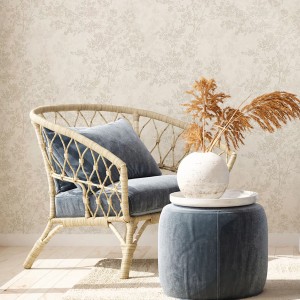 Beige Vliestapete mit Kirschblüten-Design hinter Sessel und Hocker.