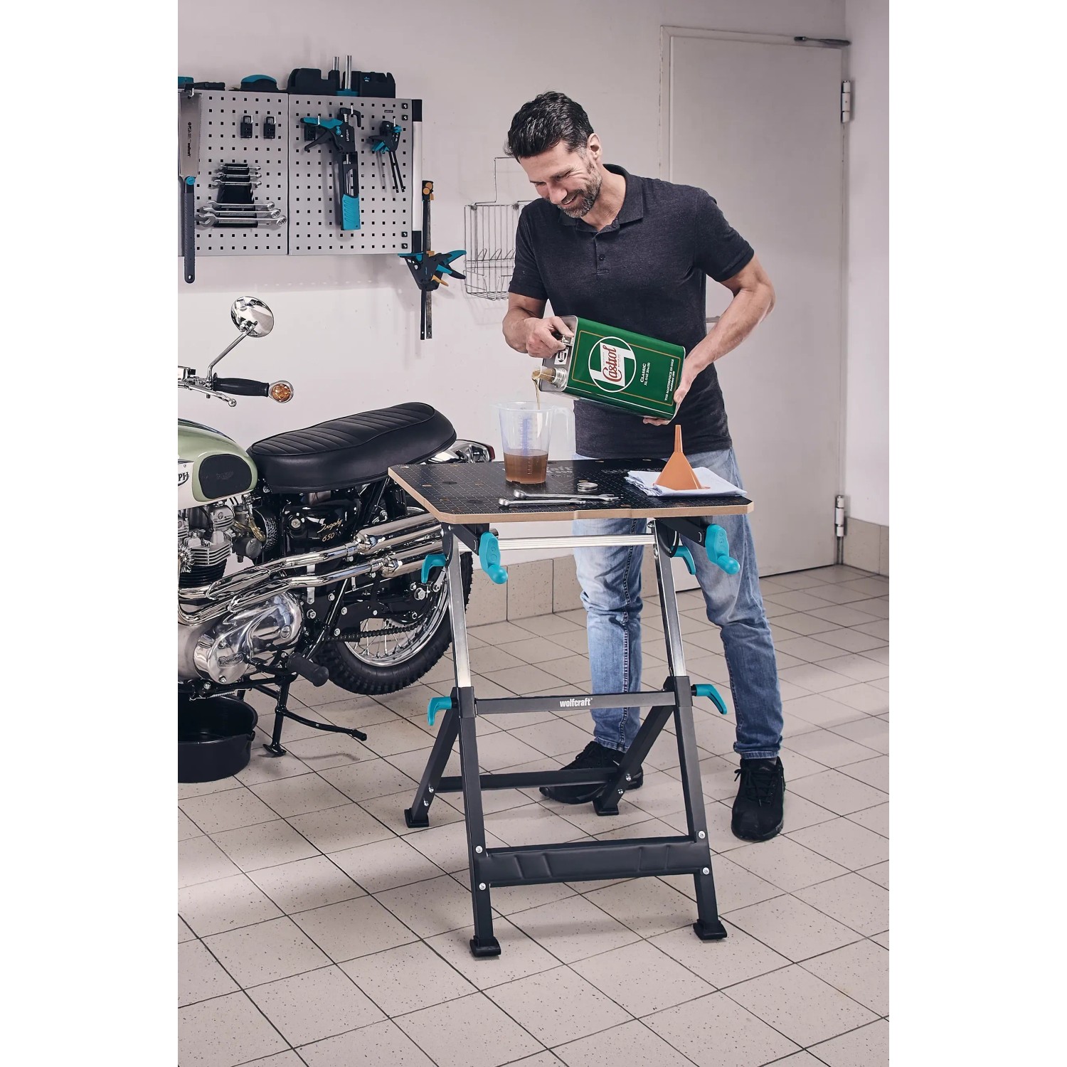 Mann arbeitet mit Wolfcraft Master 650 Ergo Werkbank in Garage. Ideal zum Spannen und Arbeiten.