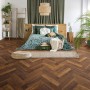 Verlegtes Kronoflooring Herringbone Laminat Laguna Oak im Schlafzimmer mit Möbeln.