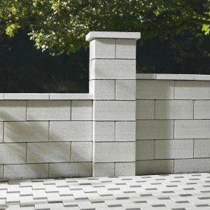 Graue Gartenmauer aus Betonsteinen mit Pfeiler und Abdeckung als Grundstückseinfassung.