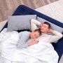 Bestway Luftmatratze Queen Size, dunkelblau, mit Paar unter weißer Decke. Camping & Gästebett.