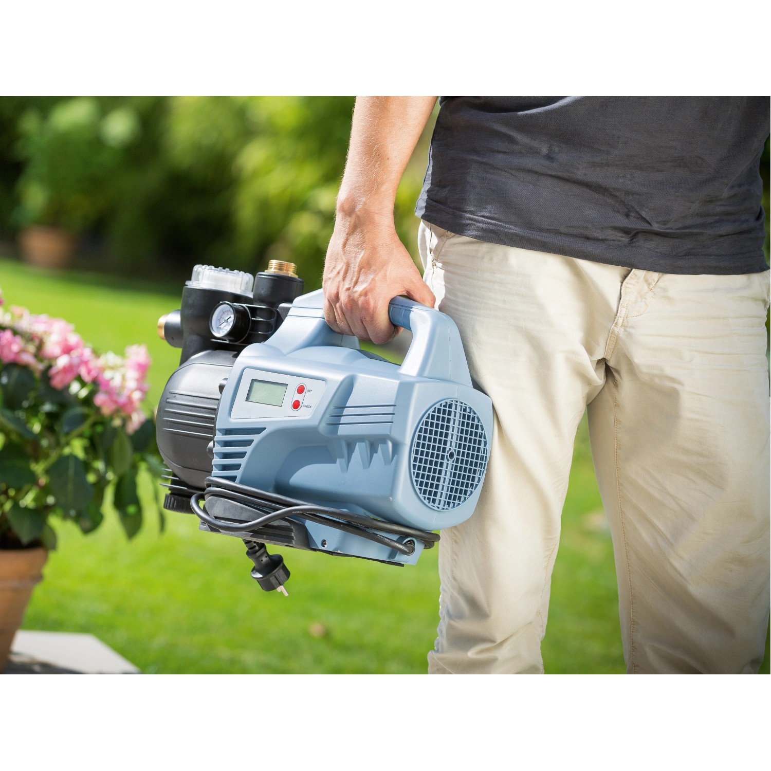 Mann trägt blauen Hauswasservollautomat HWA 4100 für Gartenbewässerung.