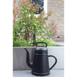 Schwarze Xala Gießkanne Lungo (12 l) vor Pflanzenkübel. Design-Gießkanne für Garten und Zuhause.