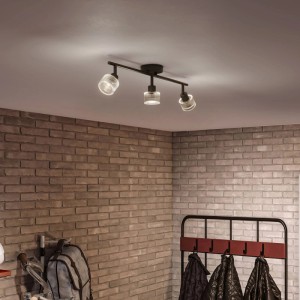 Schwarzer Philips LED-Spot Horen mit 3 drehbaren Köpfen aus strukturiertem Glas an Decke, beleuchtet Ziegelwand.