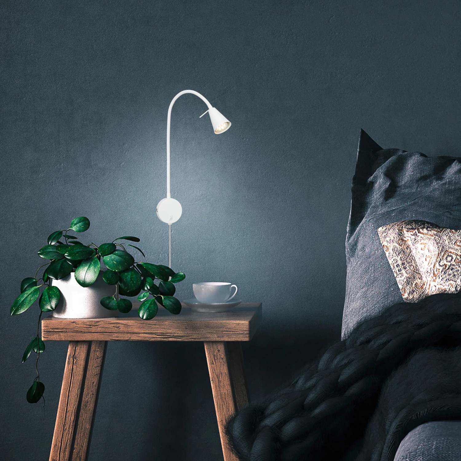 Briloner LED Bettleuchte Tusa, schwenkbar, warmweiß, montiert an blauer Wand über Nachttisch.