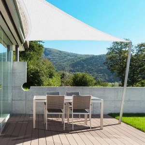 Weißes, dreieckiges Karat Sonnensegel über einer Terrasse mit Tisch und Stühlen.