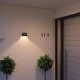 Schwarze Philips Hue Resonate LED-Außenwandleuchte mit Lichtkegel an Hauswand.