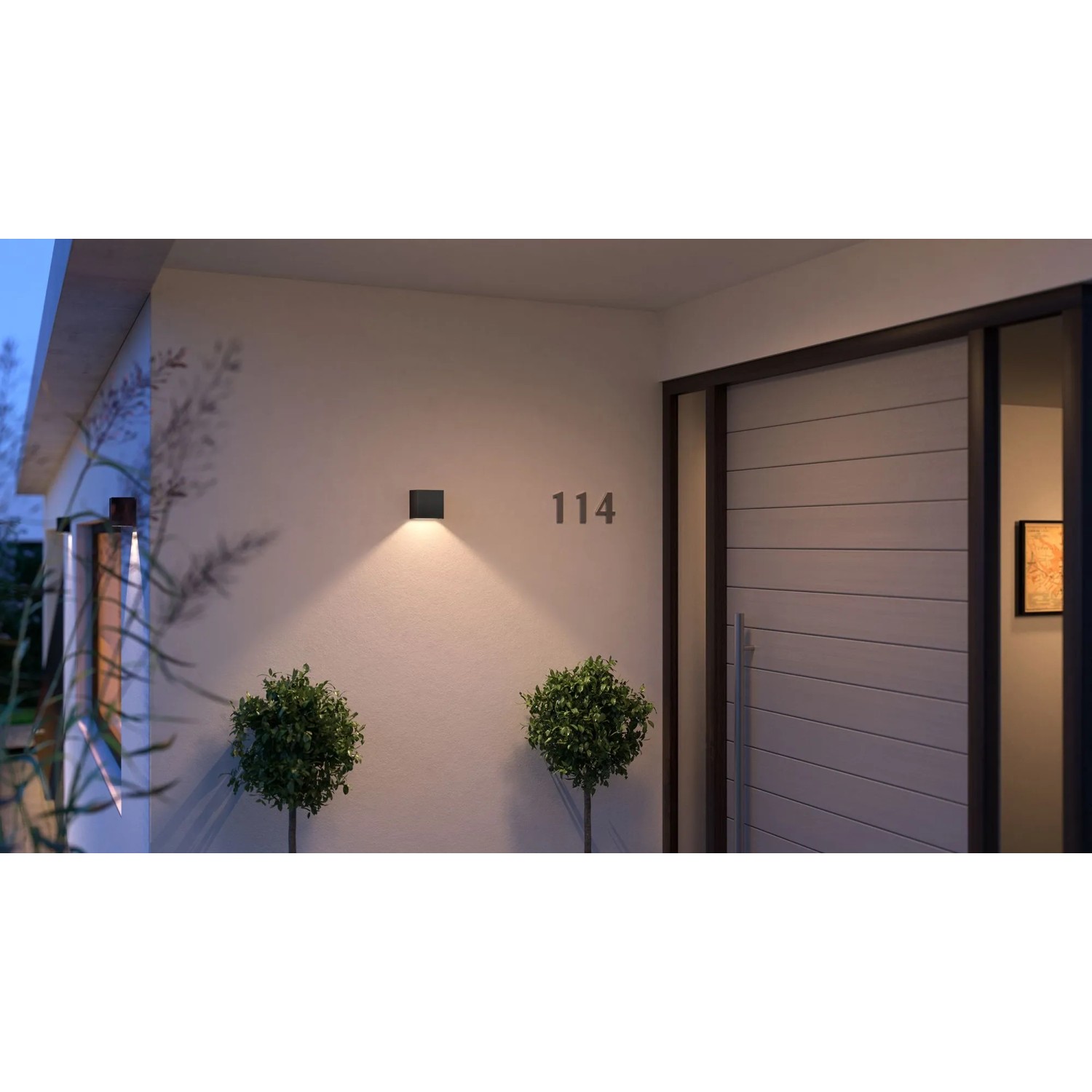 Schwarze Philips Hue Resonate LED-Außenwandleuchte mit Lichtkegel an Hauswand.