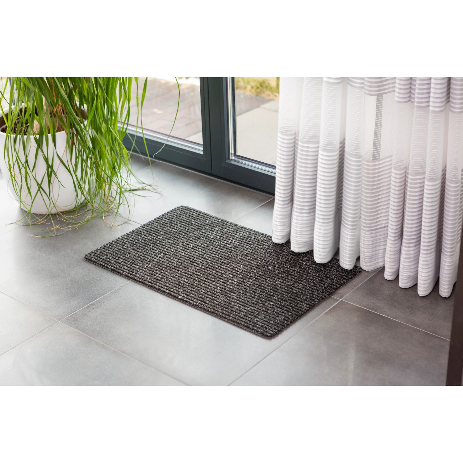 Anthrazitfarbene Astra Türmatte Rib Line Sprint 40x60 cm vor einer Tür.