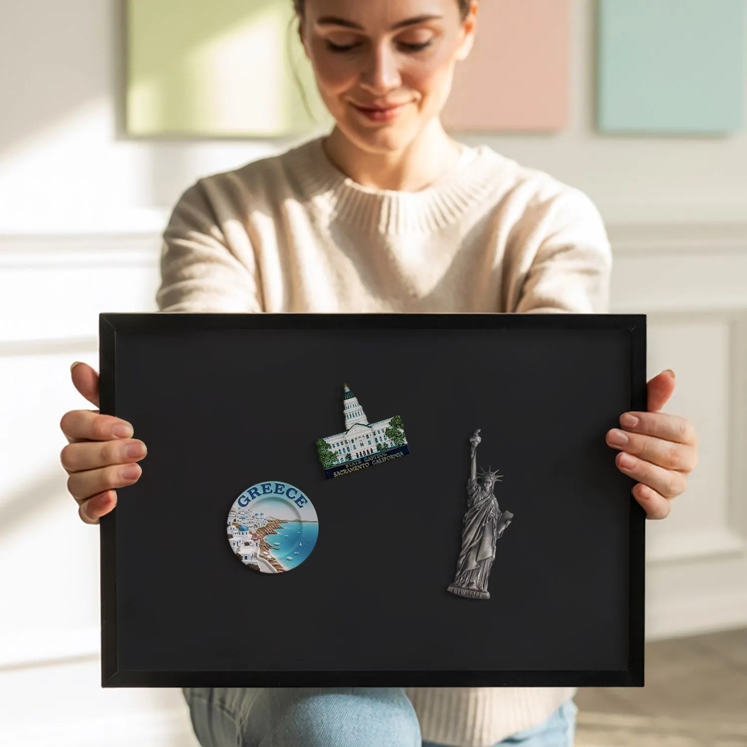 Schwarze Tulup Magnettafel 100x70 cm mit Reisemagneten, gehalten von einer Person.