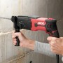 Skil Bohrhammer 1770GA beim Bohren in Betonwand, rot-schwarz, mit Zusatzhandgriff.