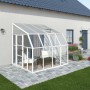 Weißes Palram Canopia Gewächshaus Sun Room (260x257cm) am Haus mit geöffnetem Dachfenster.