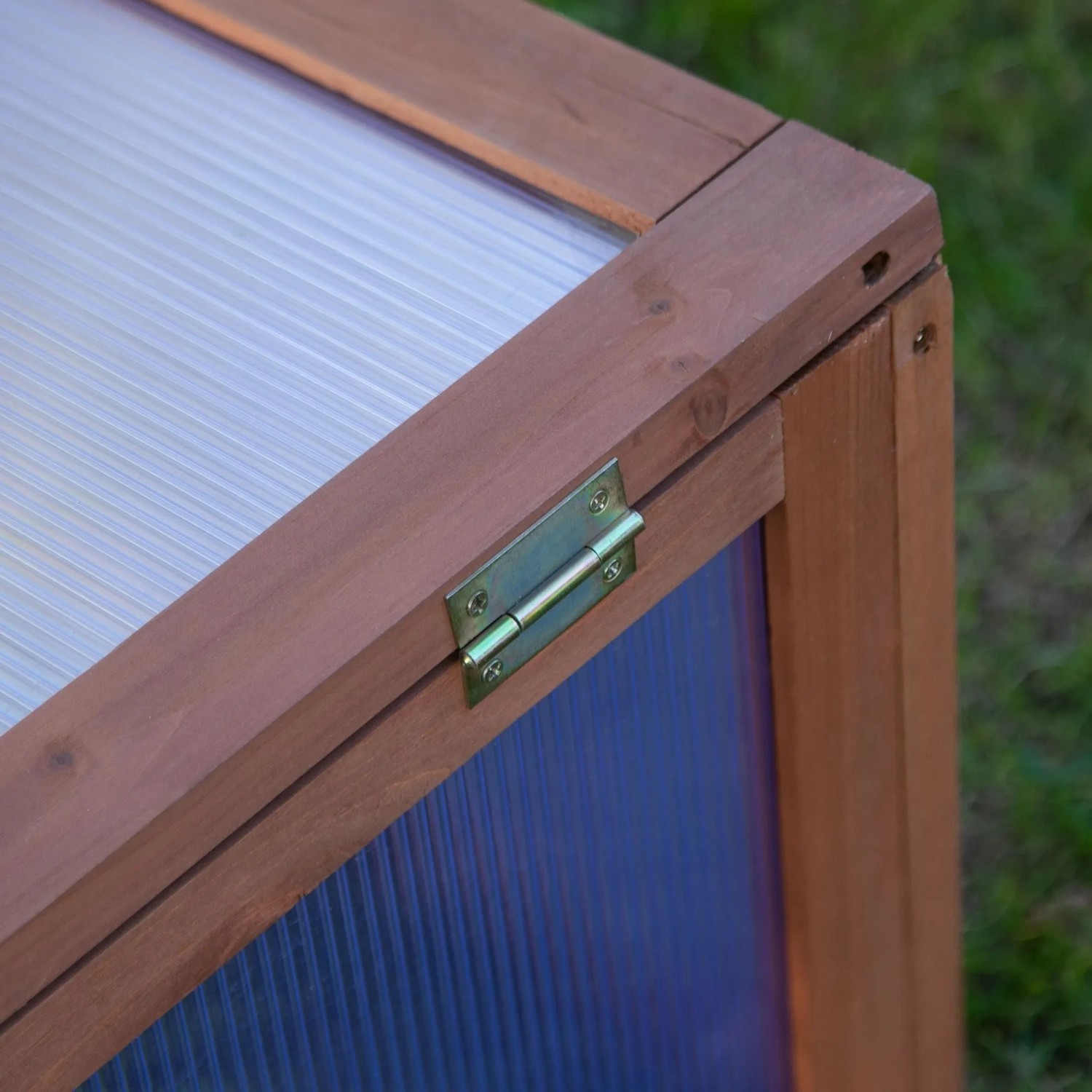 Nahaufnahme des Outsunny Gewächshauses: brauner Tannenholzrahmen, Polycarbonatplatten, Metallscharnier.