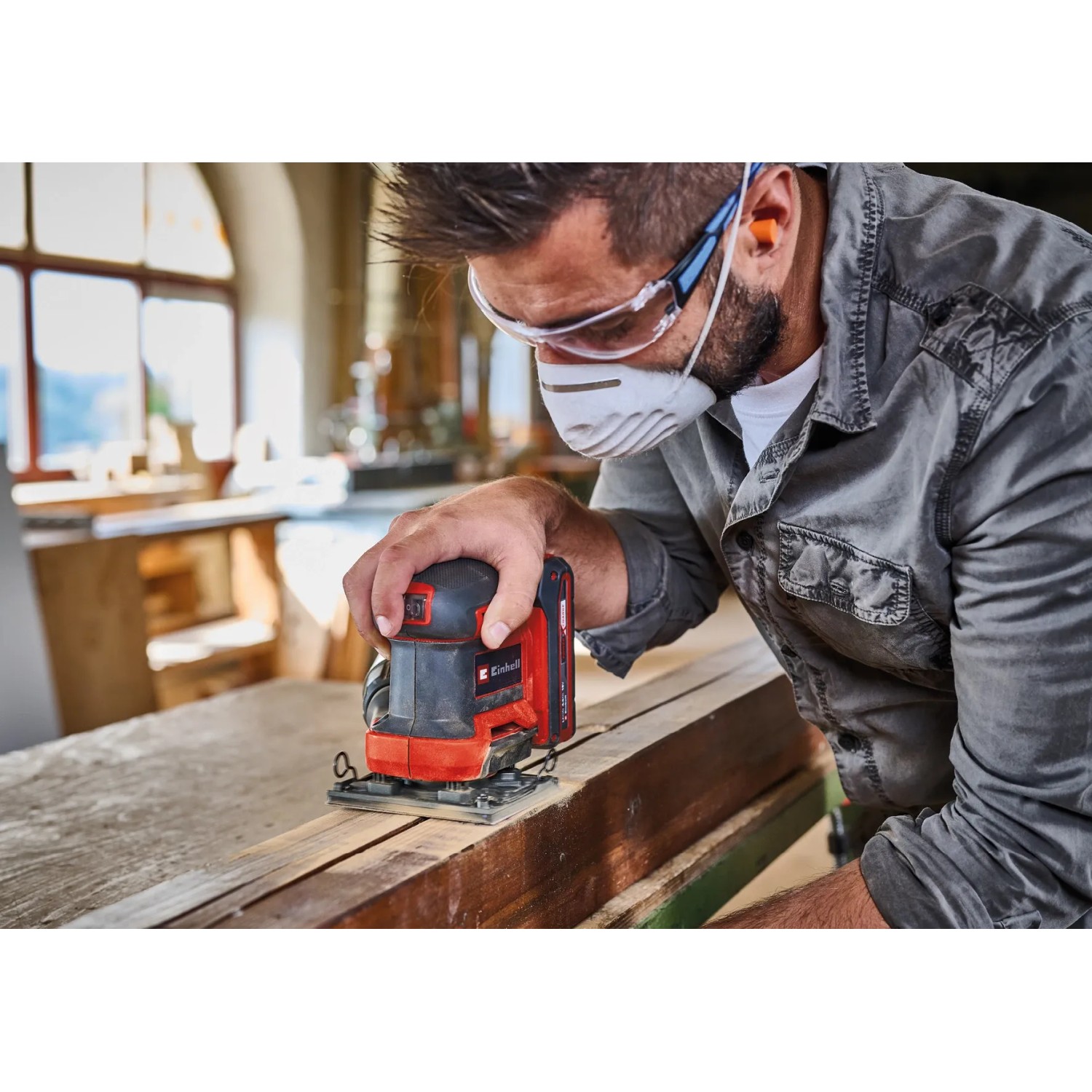 Einhell Akku-Faustschleifer TE-OS 18/113 Li-Solo im Einsatz auf Holz. Kompaktes Design, rot-schwarz.