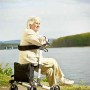 Frau ruht sich auf dem Ridder Rollator Premium in Schwarz aus, mit Blick auf einen See.