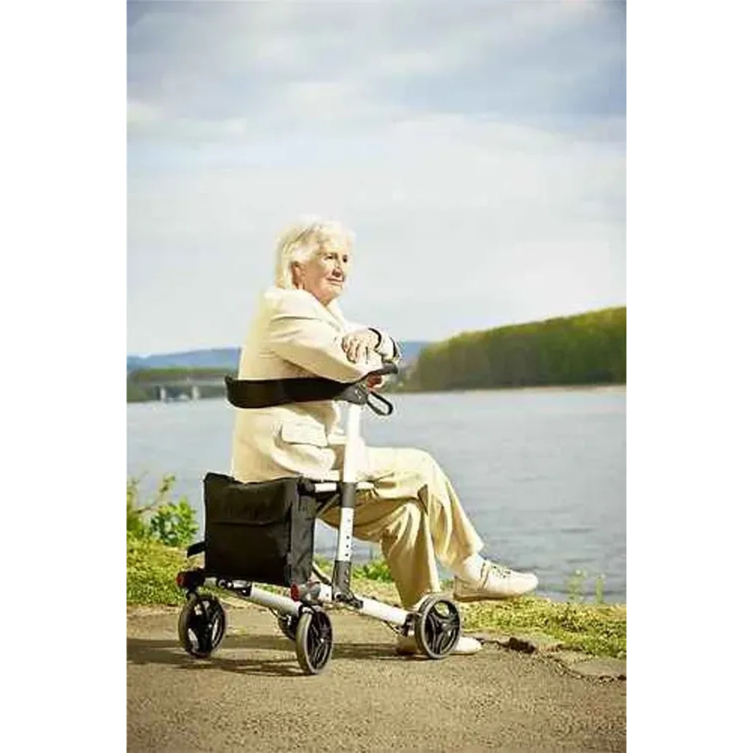 Frau ruht sich auf dem Ridder Rollator Premium in Schwarz aus, mit Blick auf einen See.