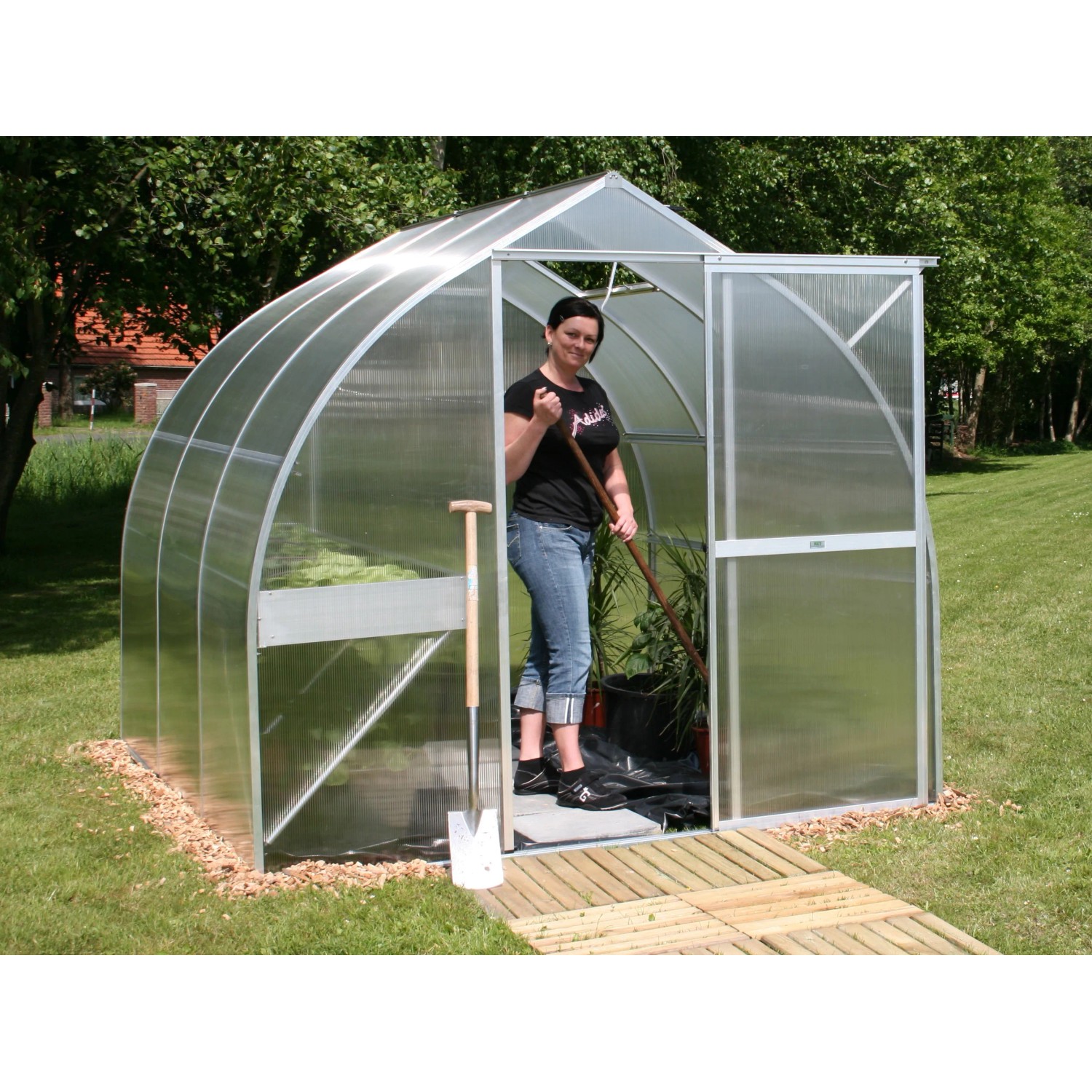 KGT Gewächshaus Alu blank 5,15 m² mit Frau und Gartengeräten im Garten.