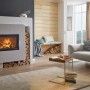 Weißer Haas+Sohn Kaminofen Komfort IV mit Wärmespeicherbeton und Holzscheiten im Wohnzimmer.