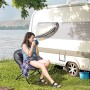 Frau sitzt entspannt im grauen Outsunny Campingstuhl aus Metall und Polyester vor Wohnwagen.