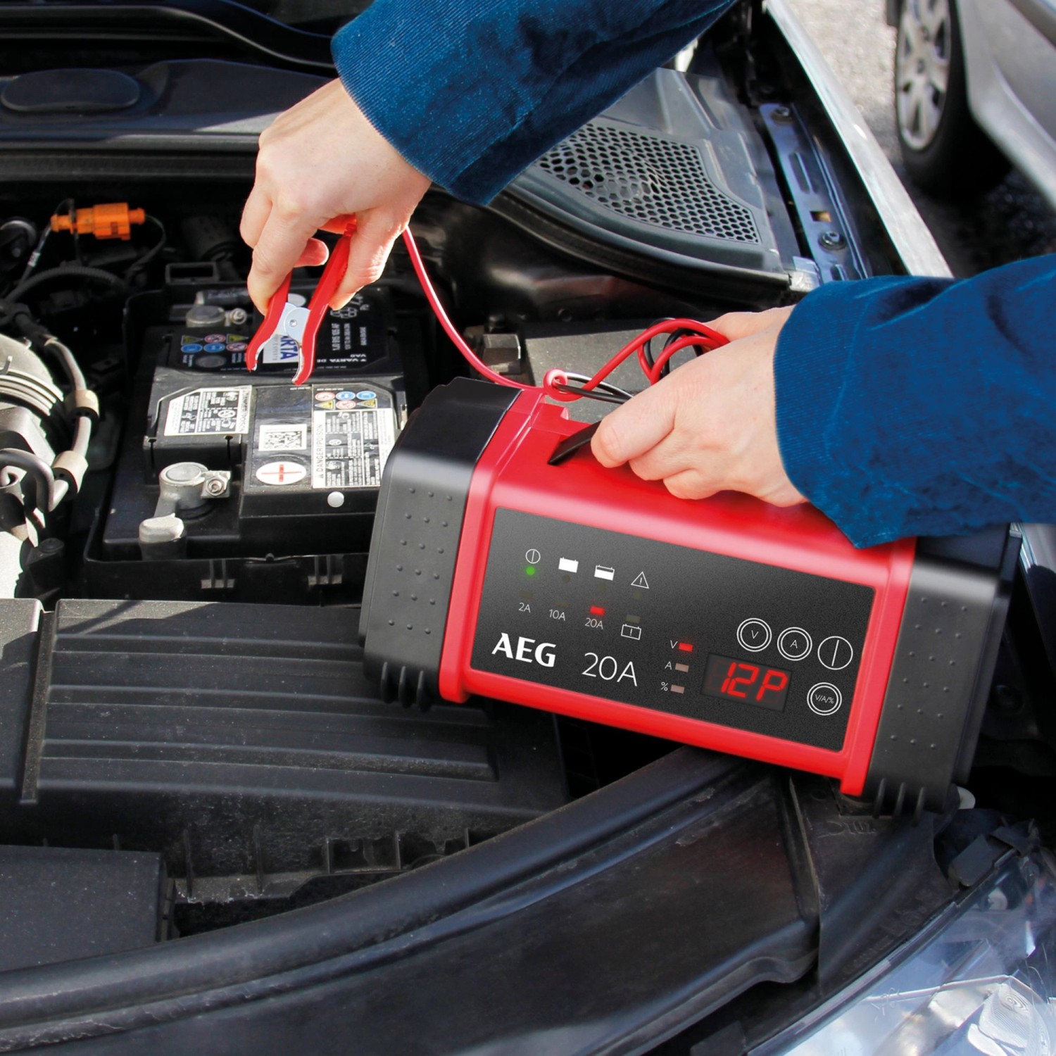 AEG Batterieladegerät LT 20 A beim Laden einer Autobatterie unter der Motorhaube.