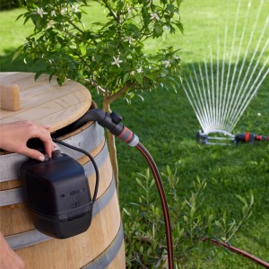 Gardena Akku-Regenfasspumpe 2600 Comfort 18V Set in Nutzung mit Regner im Garten.