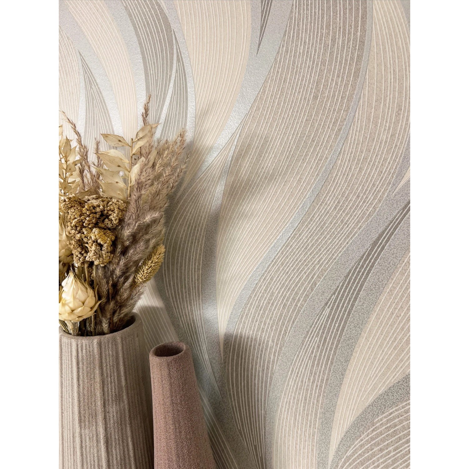 Beige Vliestapete Faria mit Wellen und Streifenmuster, kombiniert mit Vasen und Trockenblumen.