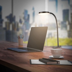 Schwarze Briloner LED-Klemmleuchte PLEGG mit Lichtkante am Schreibtisch.