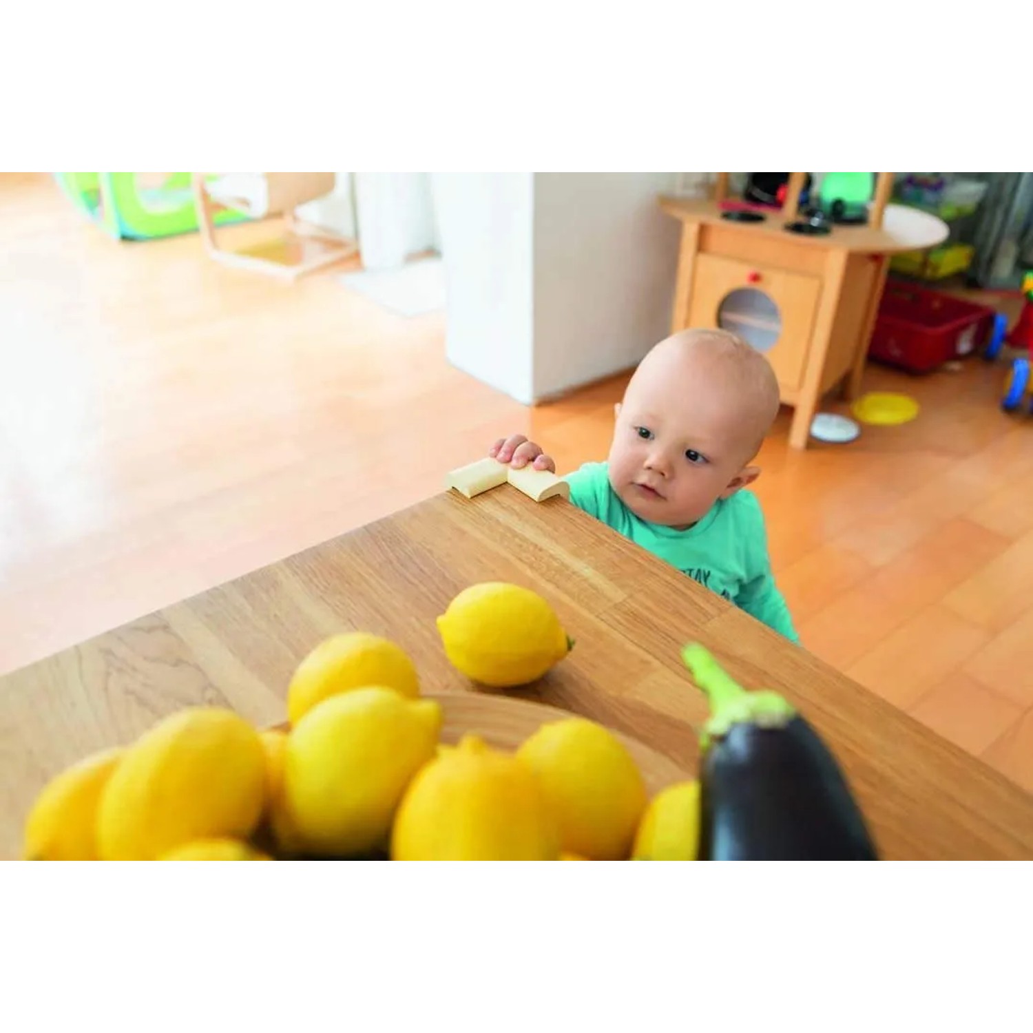 Baby am Tisch mit Abus Eckenschutz Jannic. Kindersicherung für Möbel.