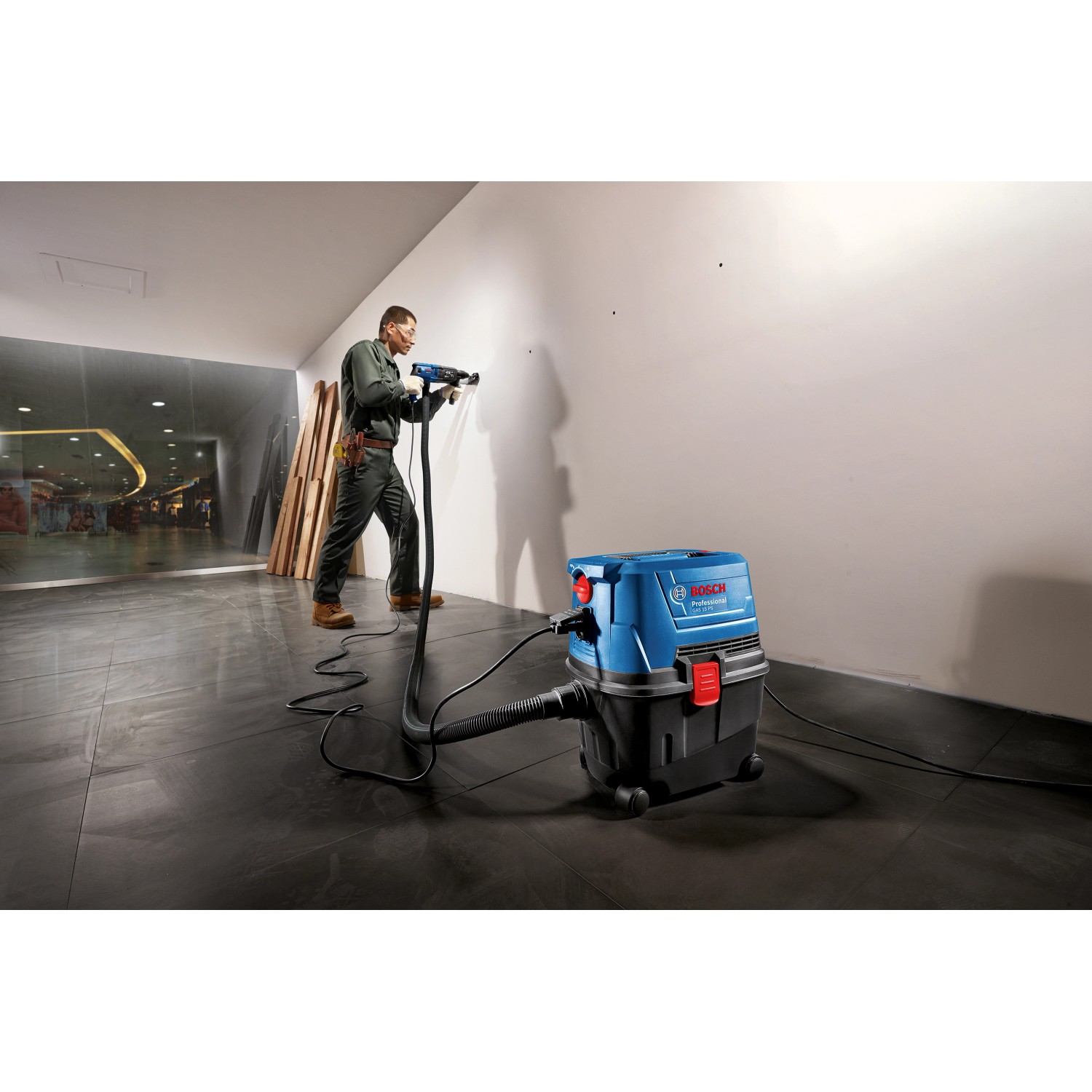 Bosch Professional GAS 15 PS Nass-/Trockensauger im Einsatz beim Bohren in eine Wand.