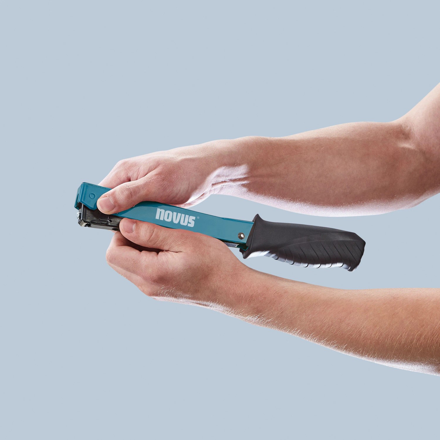 Novus Hammertacker J-022 in Aktion: Hände bedienen blauen Tacker mit schwarzem Griff.