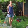 Frau bewässert Garten mit Einhell Gartenpumpe GC-GP 6538. Elektro-Pumpe mit Schlauch und Spritze.