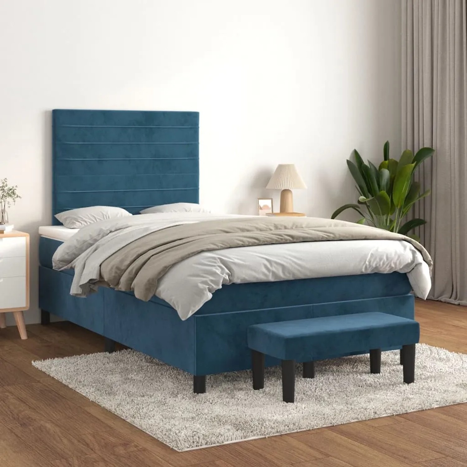 Dunkelblaues Boxspringbett (120x200 cm) mit Matratze, Kopfteil und Bank aus Samt.