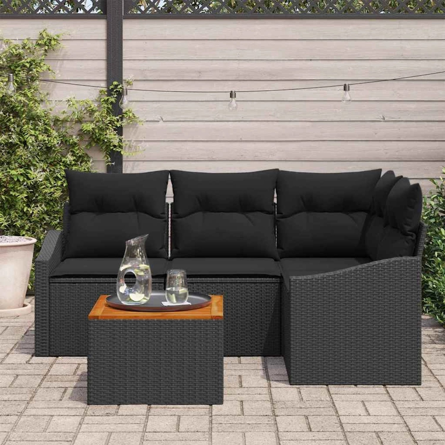 Schwarzes 5-teiliges Garten-Sofa-Set aus Poly Rattan mit Kissen und Tisch.