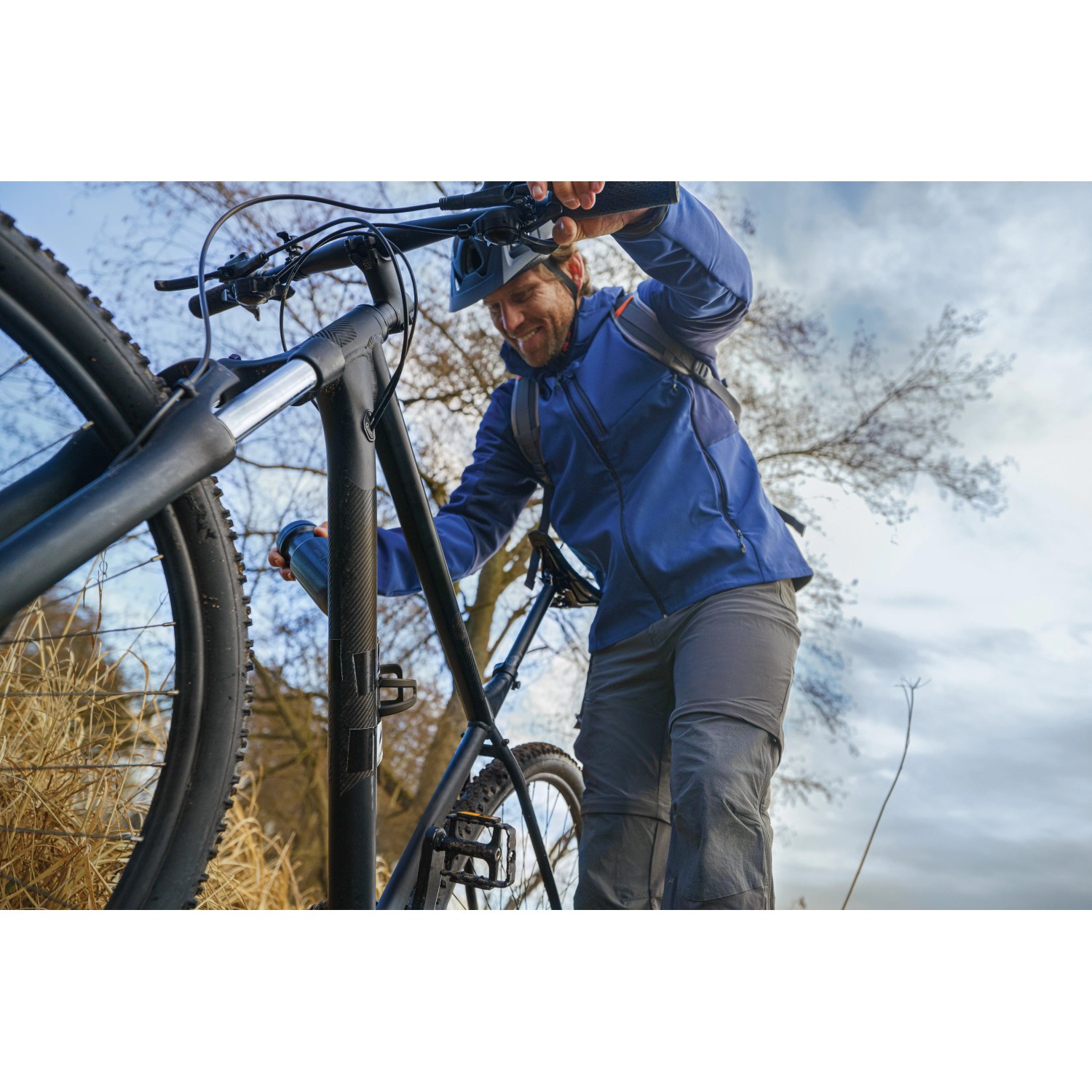 Mann schiebt Fahrrad, gesichert mit Tesa Ultra Power Extreme Reparaturband, für Outdoor-Abenteuer.