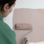 Frau streicht Wand mit Farbroller aus Wallpro Werkzeug-Set, Tapezierwerkzeug.