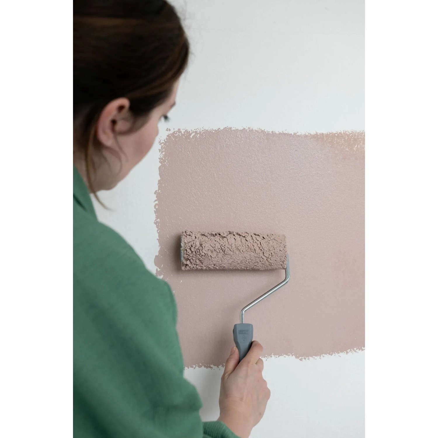 Frau streicht Wand mit Farbroller aus Wallpro Werkzeug-Set, Tapezierwerkzeug.